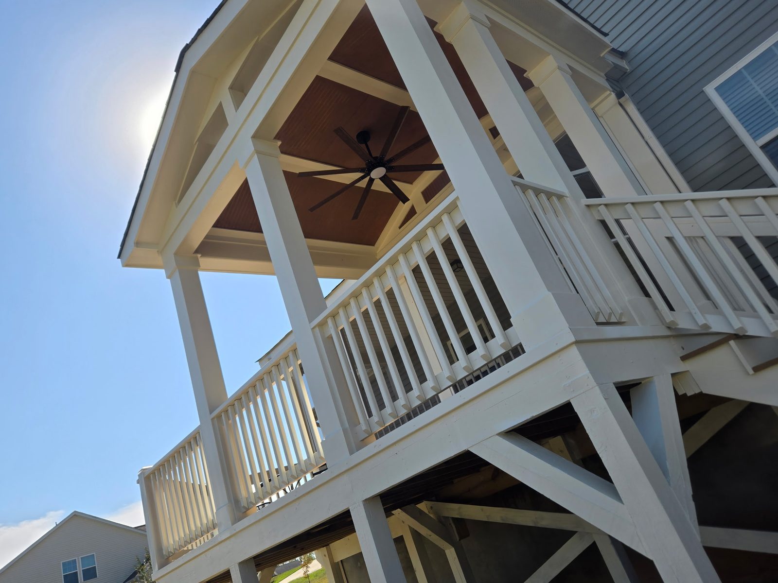 Covered porch with vaulted stained-wood ceiling and ceiling fan